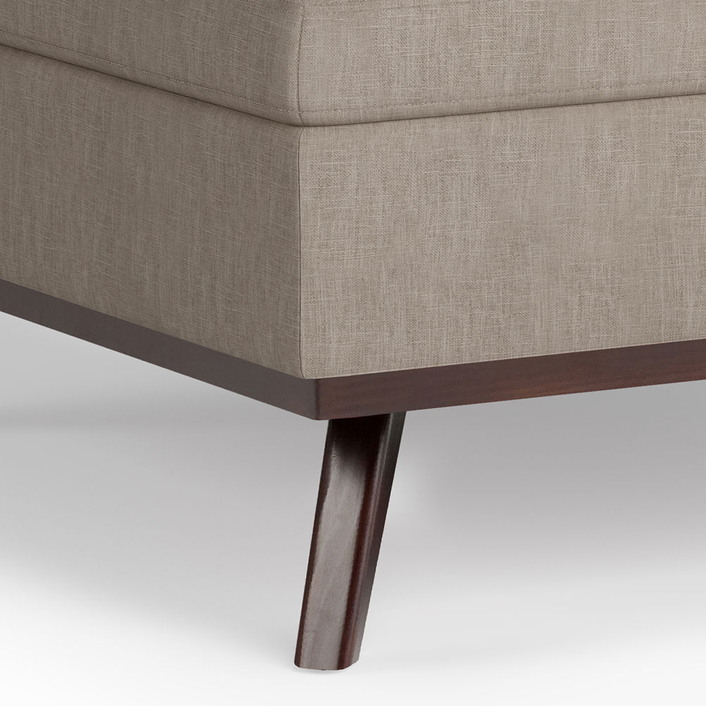 Close-up of the Owen Multifunctional Square Coffee Table Storage Ottoman in beige upholstery with wooden legs and a dark wood base, set against a plain white background.