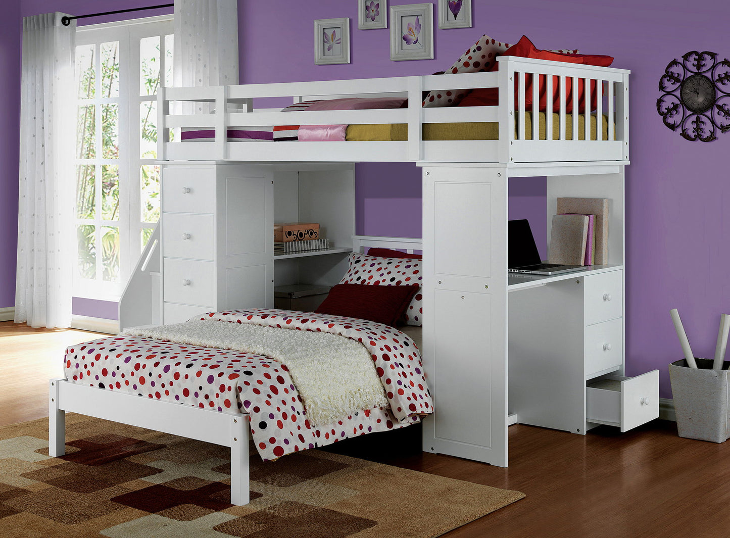 A modern bedroom featuring the Freya Twin Loft Bed With Storage in white above a desk and drawers, a lower twin bed with red and beige polka dot bedding, purple walls, large windows with sheer curtains, and a patterned rug on hardwood floors.
