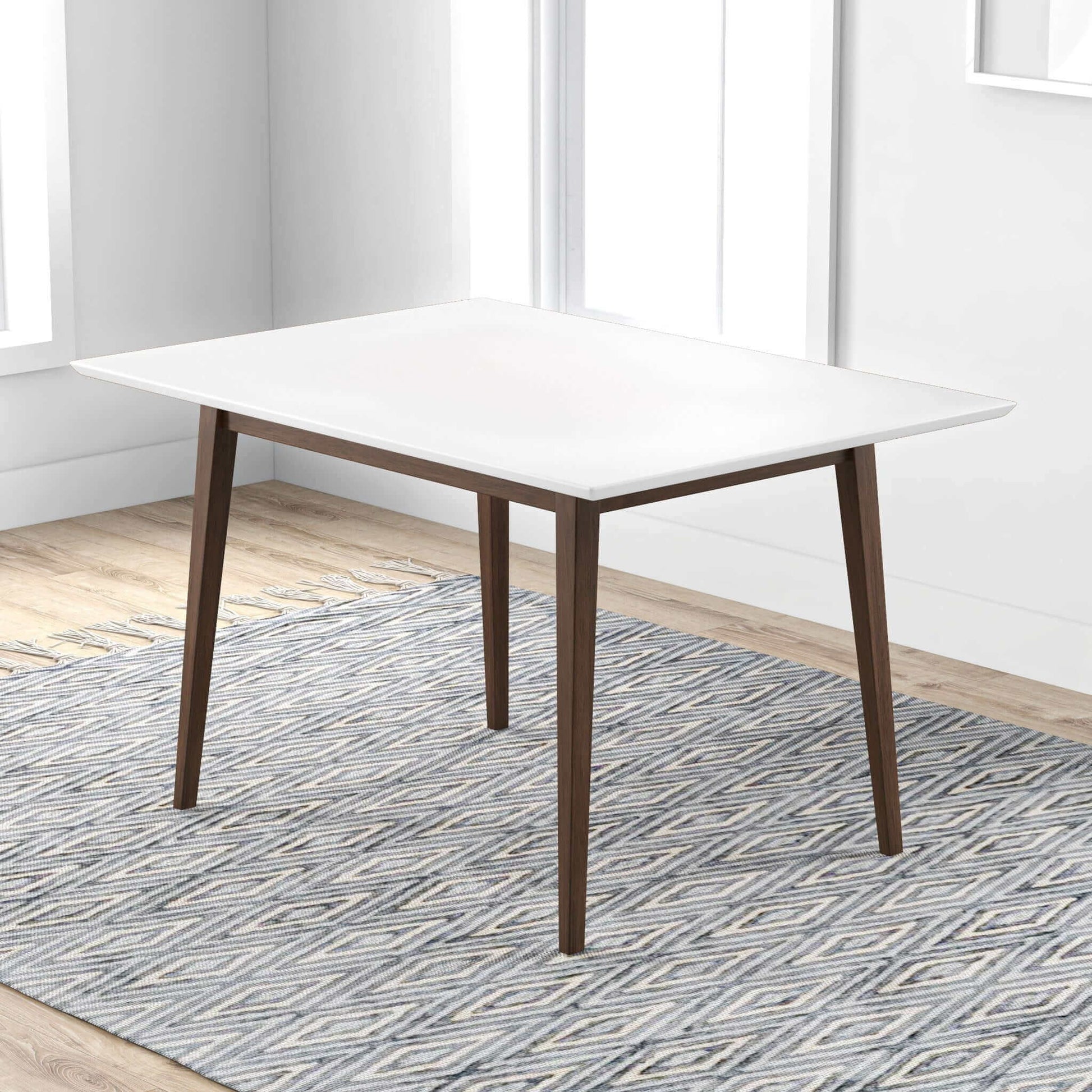 The Levi - Modern Style Rectangular Dining Kitchen Table with a white top and wooden legs stands on a patterned gray and white rug in a bright room featuring light wood floors and large windows.