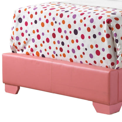 An Elegant Platform Bed For Relaxed Spaces is topped with a white comforter featuring orange, red, and purple polka dots in various sizes, while a pink upholstered bench sits at its foot.