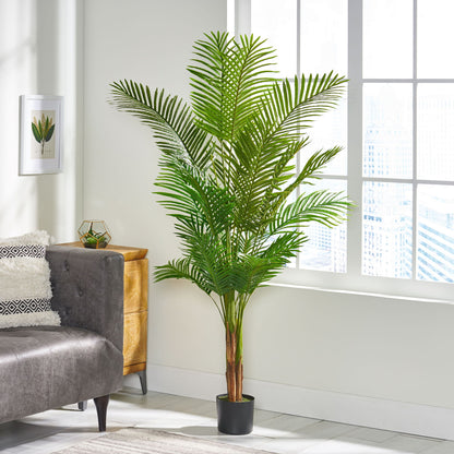 An Artificial Palm Tree with lush green fronds stands beside a gray couch in a bright, modern living room featuring a large window and decorative wall art.
