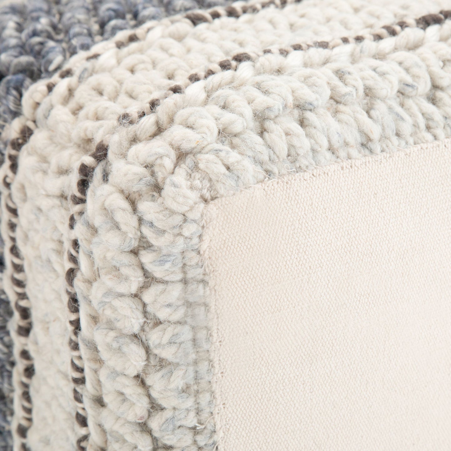 Close-up of the Grady - Handcrafted Square Pouf featuring thick, chunky knit edges in cream and gray with a smooth, light beige fabric panel at the center.