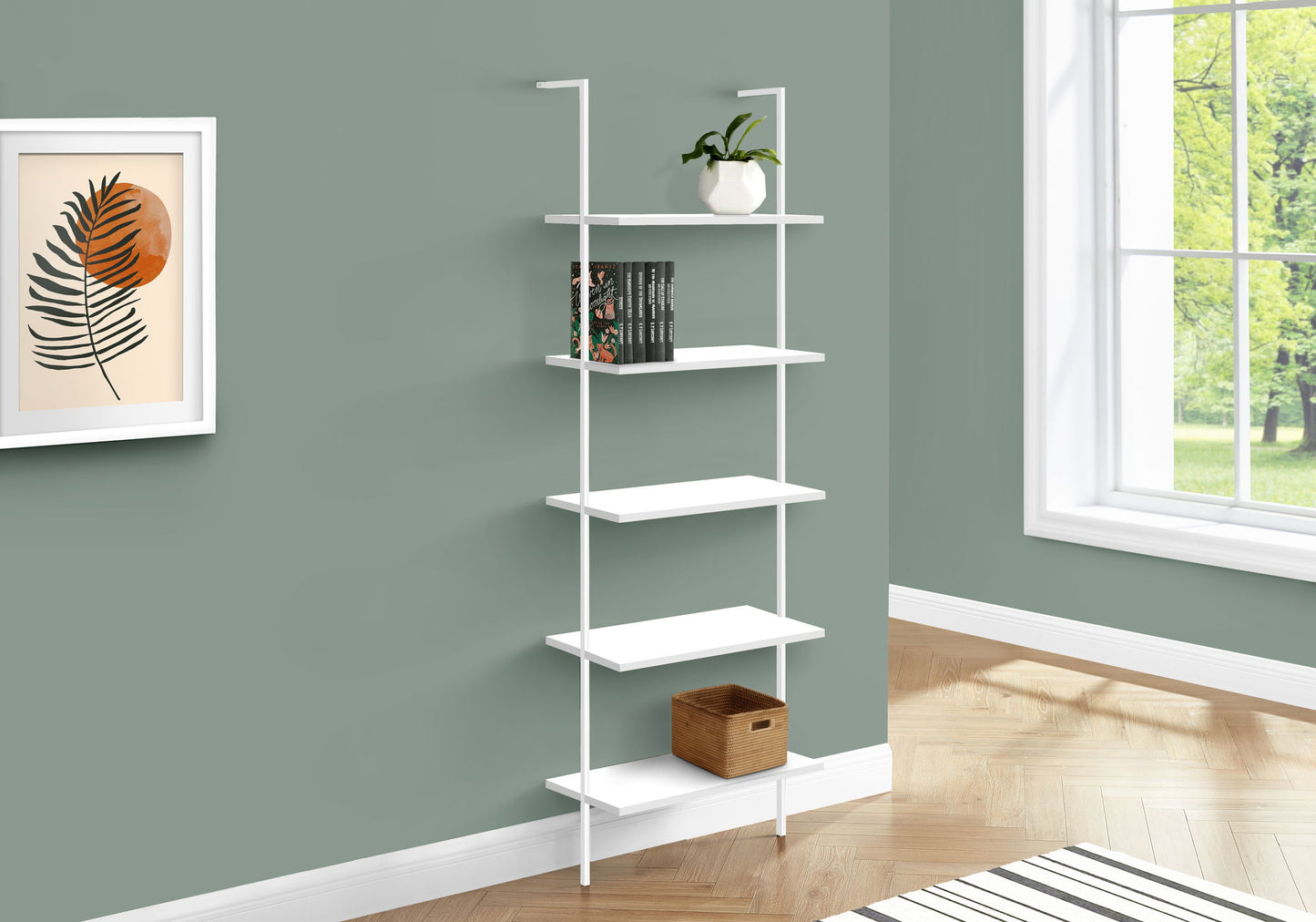 The Etagere Bookcase Ladder 5 Tier For Office, a white wall-mounted shelving unit, displays a plant, books, and a wicker basket against a green wall near a window, with a framed leaf print on the nearby wall.