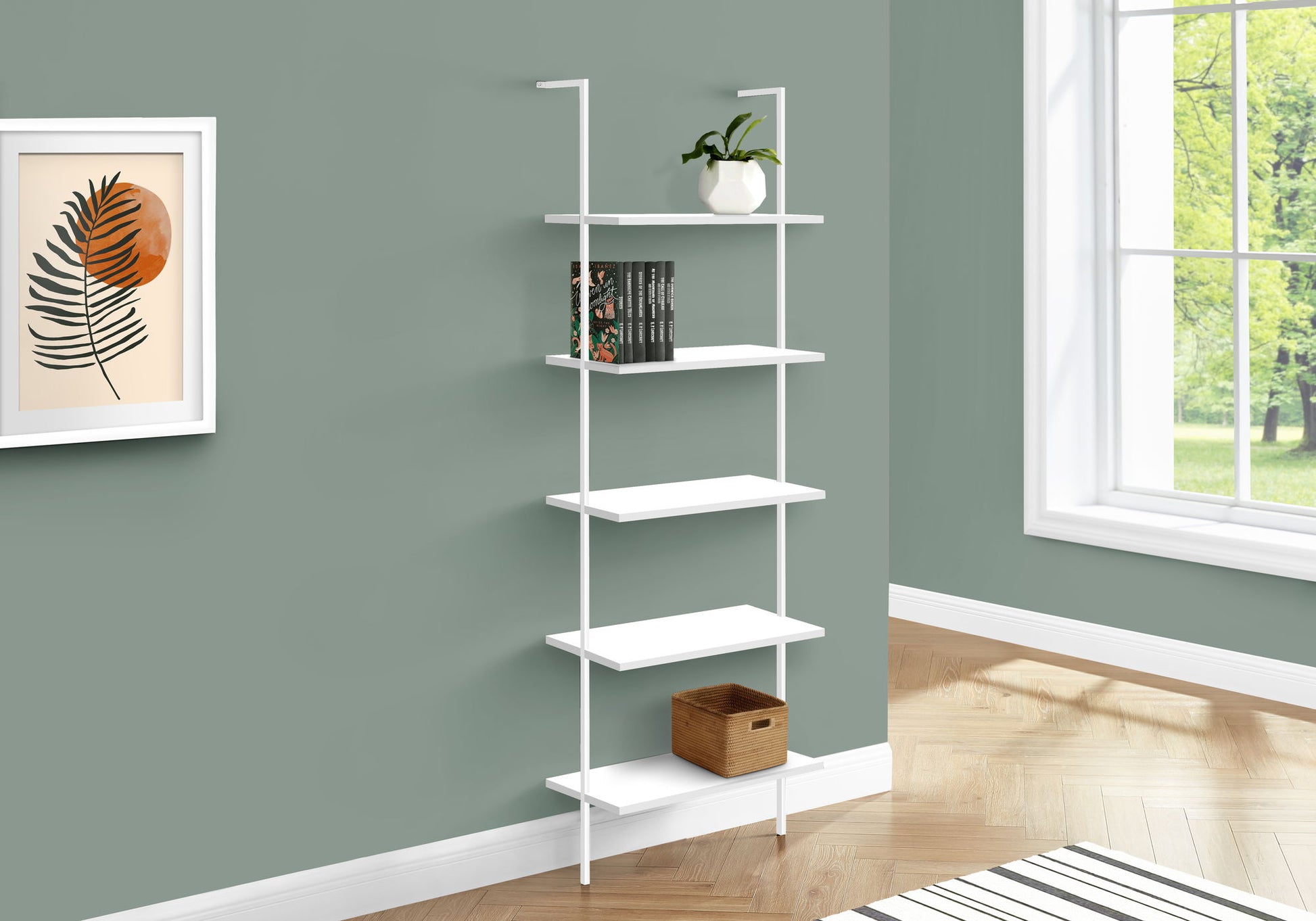 The Etagere Bookcase Ladder 5 Tier For Office, a white wall-mounted shelving unit, displays a plant, books, and a wicker basket against a green wall near a window, with a framed leaf print on the nearby wall.