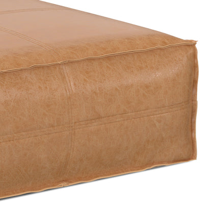 Close-up of the Brody Large Square Coffee Table Pouf, featuring tan leather with visible stitching and a slightly textured surface, set against a white background.