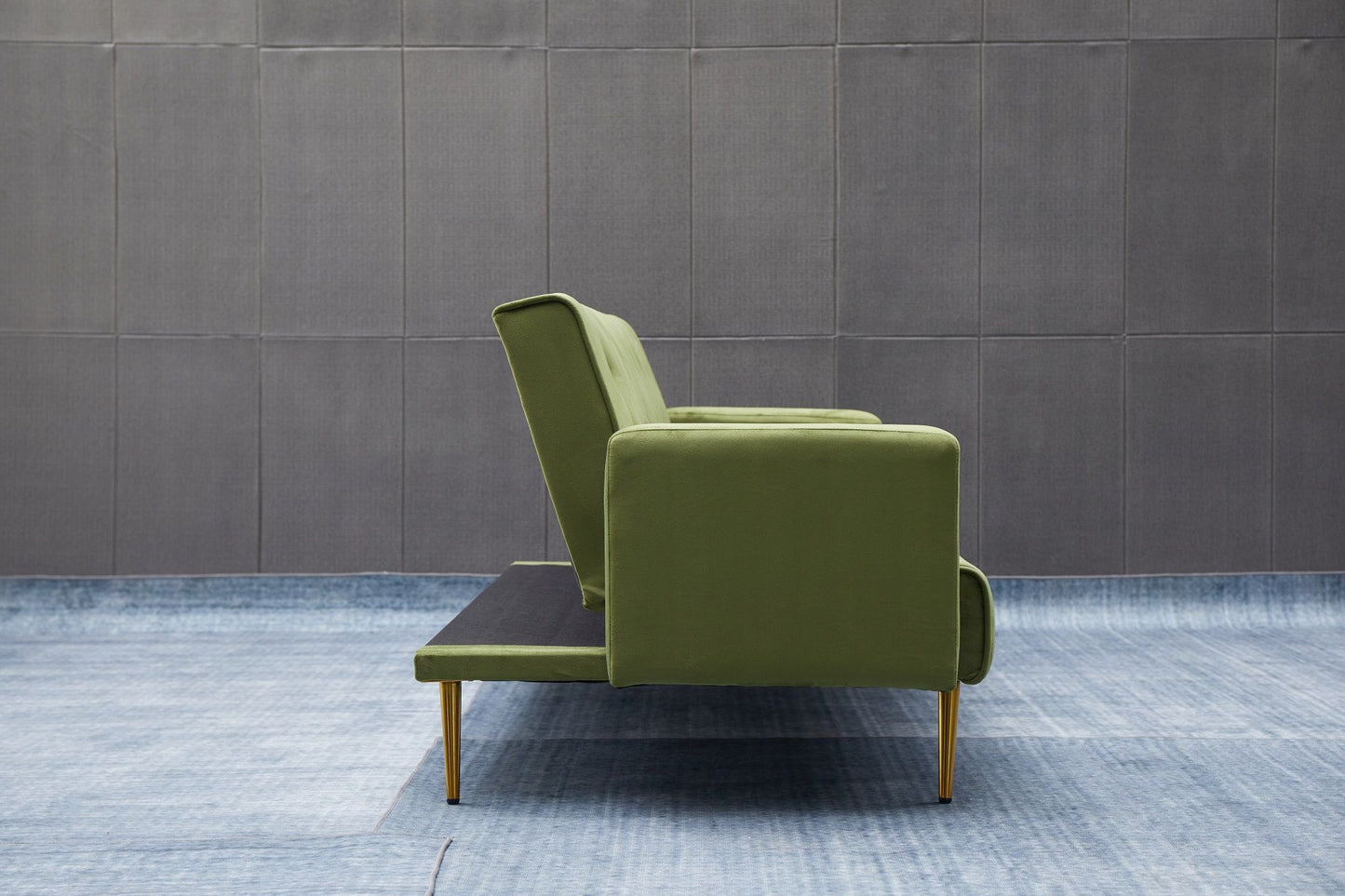 The Comfort Compact Design Sofa Bed, featuring a green modern look with gold legs, is displayed from the side on a blue rug in front of a gray tiled wall.
