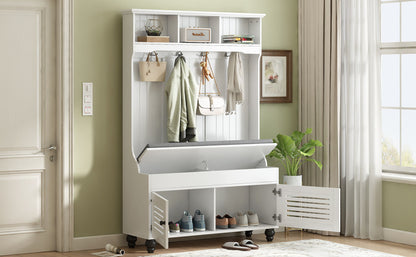 The 5 In 1 Entryway Bench features a cushioned seat, coat rack with four sturdy hooks holding bags and coats, shutter-shaped doors, and open storage for shoes. It sits against a light green wall near a window with sheer curtains.