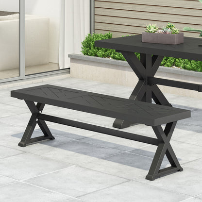A Modern Aluminum Outdoor Dining Bench With X Base in black sits on a tiled patio beside a matching table with a rectangular planter of succulents, framed by glass doors and a small garden bed.
