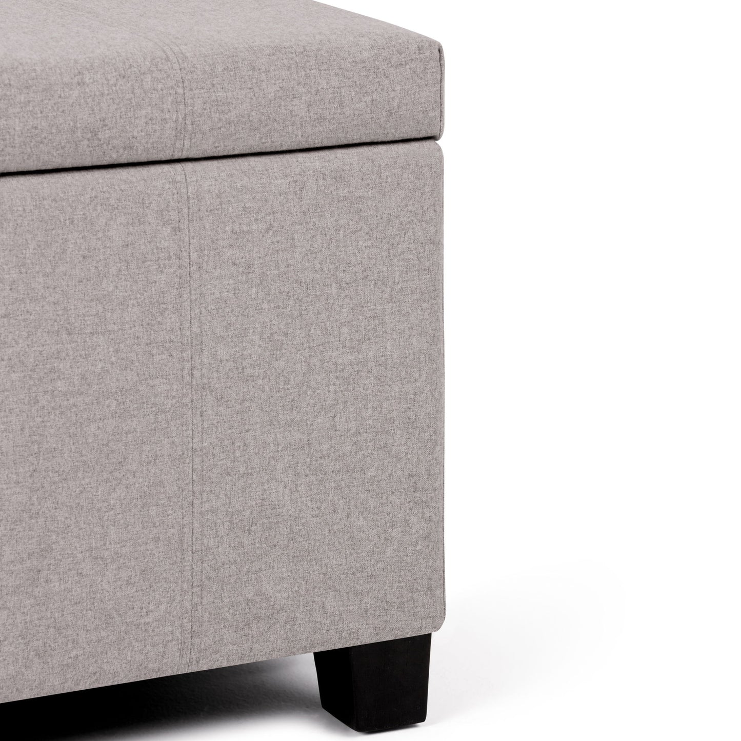 Close-up of the corner of the Dover - Upholstered Storage Ottoman Bench in light gray fabric with black wooden legs, shown against a white background.
