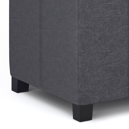 Close-up of the lower corner of the Dover - Upholstered Storage Ottoman Bench in dark gray textured fabric with short black square legs, shown against a white background.