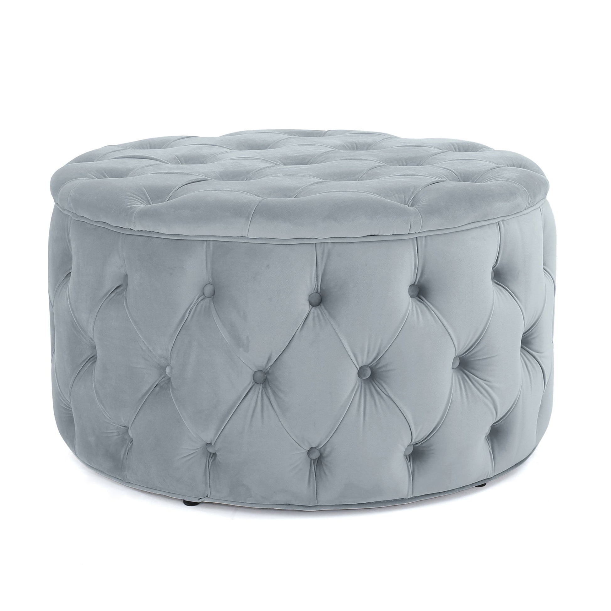 The Modern Glam Ottoman Velvet is a round, light grey ottoman with tufted velvet-like upholstery and deep button detailing on the sides and top.