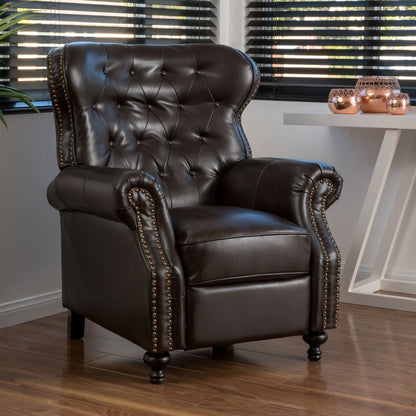 A Contemporary Style Push Back Recliner with button tufted stitching and nailhead trim sits on a wooden floor by a window with blinds, next to a white table displaying decorative candles.