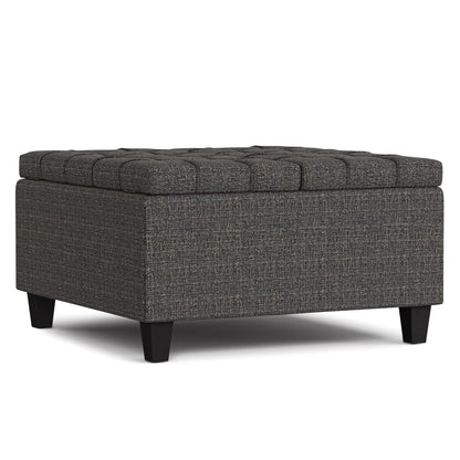 The Harrison Upholstered Coffee Table Storage Ottoman features a square, dark gray tufted design with short black legs, textured fabric, a cushioned top, and offers versatile use as seating, footrest, or storage.