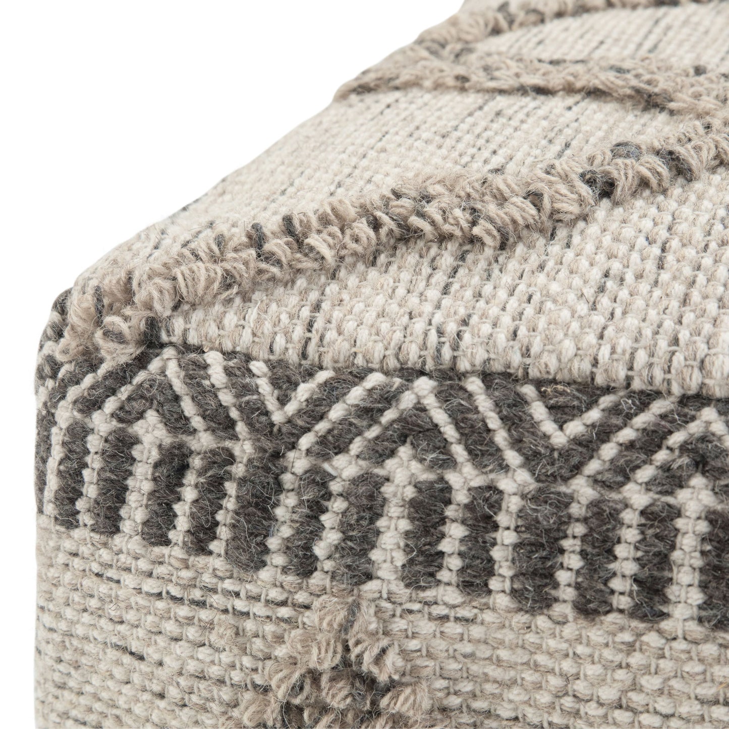 Close-up of the Sweeney - Upholstered Square Pouf featuring a textured, geometric pattern in beige and gray. The image highlights the corner with detailed stitching and raised decorative elements.