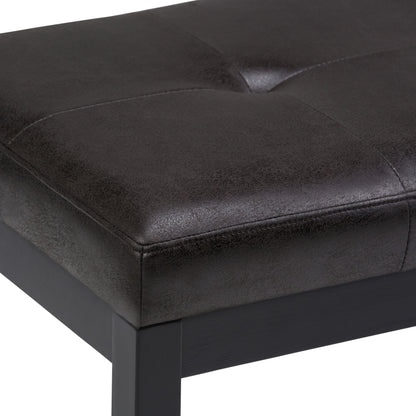 A close-up view of the Lacey - Upholstered Tufted Ottoman Bench, featuring black faux leather with visible stitching and a dark wooden frame.