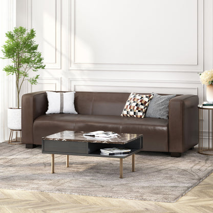 A modern living room featuring the Contemporary 3 Seater Sofa With Tuxedo Design in brown leather, three decorative pillows, a marble-top coffee table with books, a potted plant, and a light patterned rug on wooden flooring against white paneled walls.