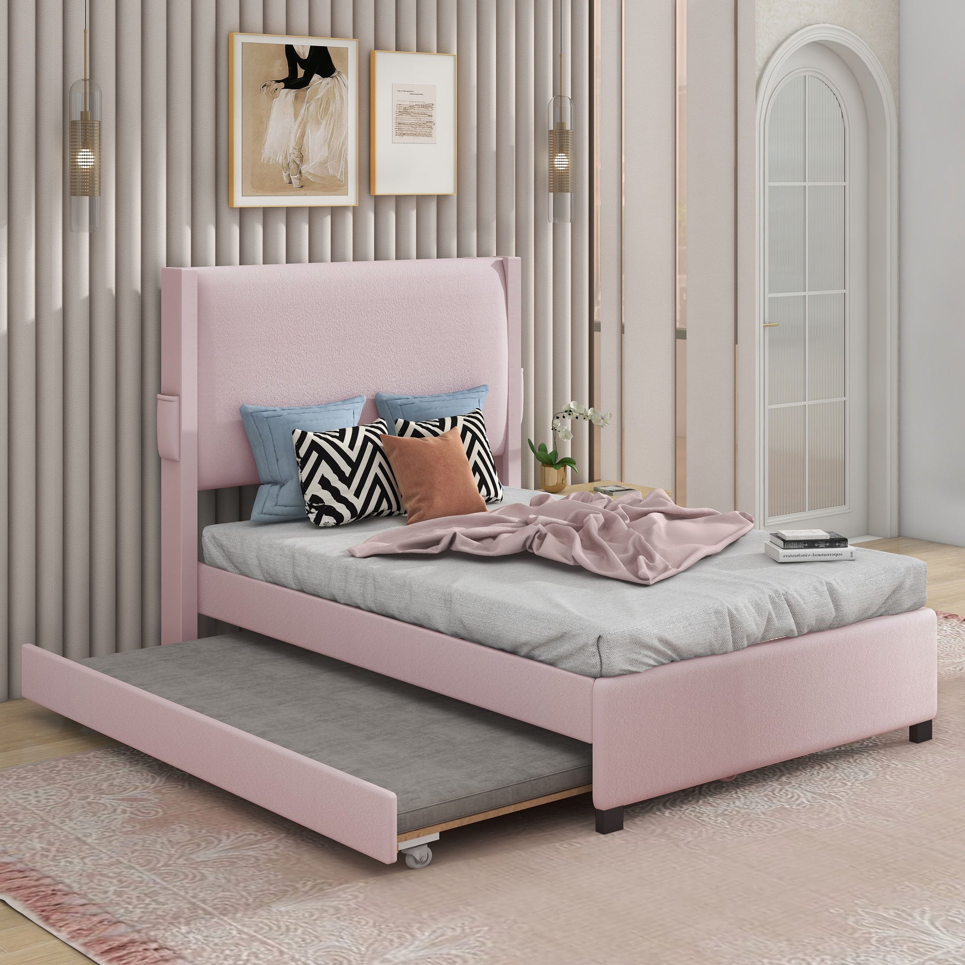 A modern bedroom with a baby pink teddy fabric twin bed frame featuring a pull-out trundle, USB port, side pocket for small items, patterned cushions, gray blanket, wall art, pendant lights, and an arched mirror.