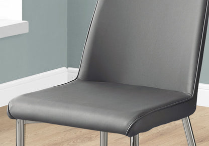 A close-up of the Contemporary Upholstered Dining Side Chair (Set of 2), featuring a padded seat and backrest with metal legs, shown on a wooden floor beside a light blue wall and white baseboard.