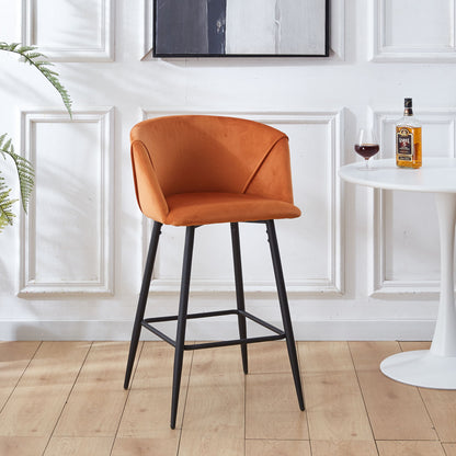 A Counter Height Bar Stool Metal Legs (Set of 2) in orange upholstery stands next to a round white table with liquor and a potted plant, set against stylish white paneled walls.