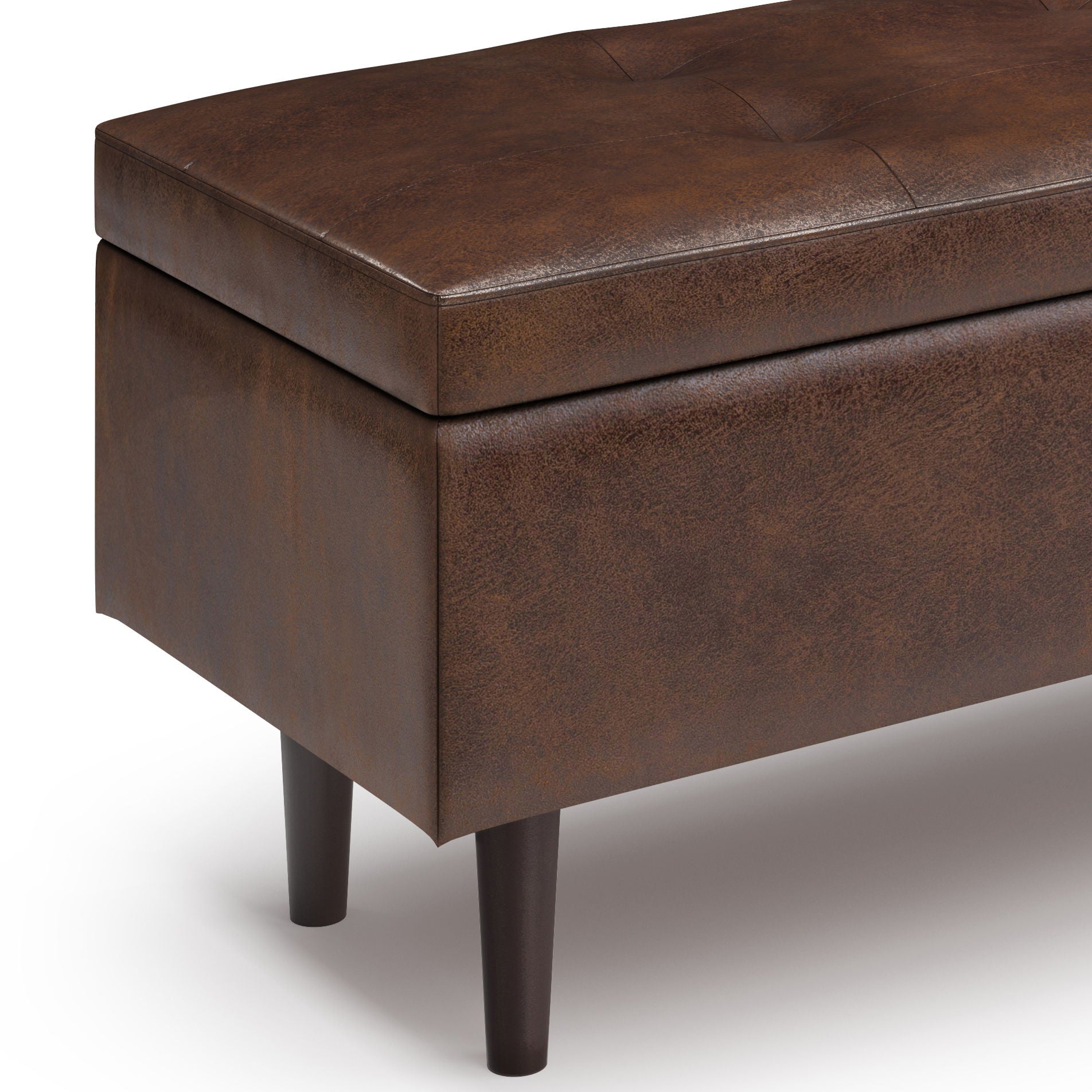 A close-up of the Shay Large Square Coffee Table Storage Ottoman in brown, featuring a tufted faux leather cushioned top and dark wooden legs, shown against a white background.