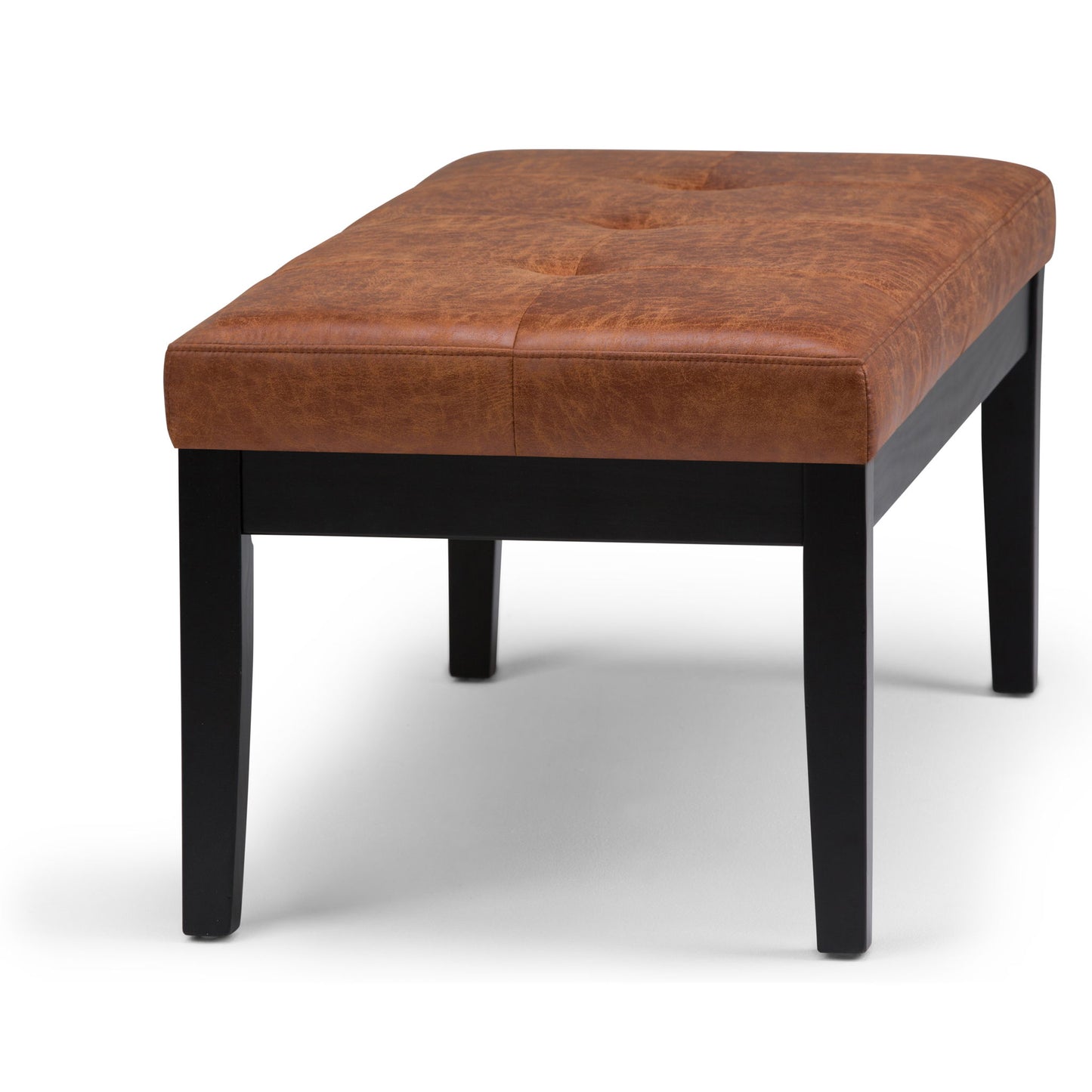 The Lacey - Upholstered Tufted Ottoman Bench features a rectangular, cushioned brown leather seat with subtle tufting and four black wooden legs, shown against a white background.