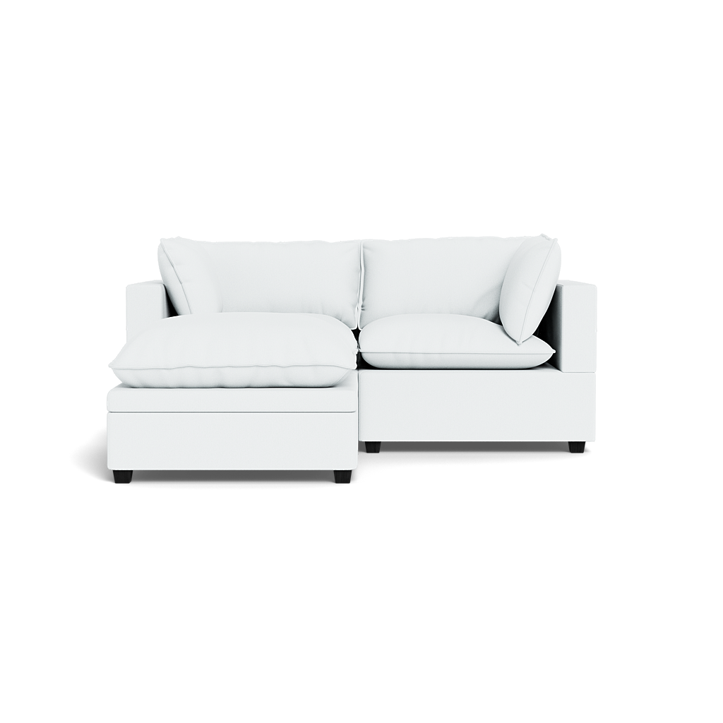The Kova Pillow Cushion Sofa 86" + Ottoman is a modern white sectional with cushioned seats and backrests, shown from the front against a plain black background.