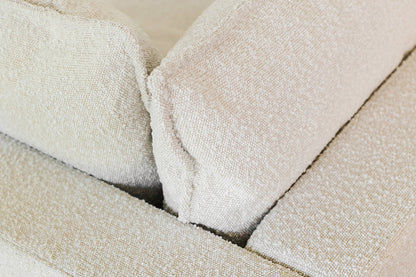 Close-up of the Kova Pit featuring a beige textured fabric with two large back cushions, highlighting its soft and cozy material.