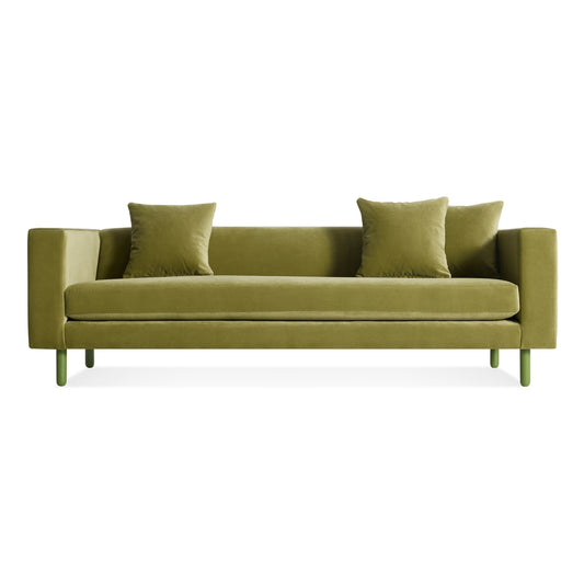 The Mono Sofa in Loden Green Velvet features a modern design with clean lines, two matching square cushions, and green cylindrical legs, set against a white background.