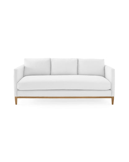 The Barton Sofa is a modern white piece featuring three cushions set against a clean, white background. It boasts a minimalist design with wooden legs, offering a stylish and contemporary look.