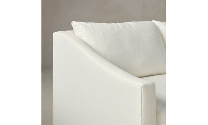 Close-up of The Sullivan 60" Sofa in Performance Linen Weave, featuring a white modern design with smooth fabric and an angled armrest. The backdrop is a soft beige, accentuating the cushion on the sofa.