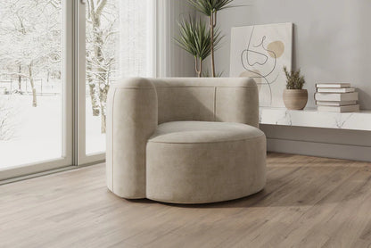 A modern living room featuring the Mellow Sectional Sofa by Acanva in a light beige, set elegantly on a wooden floor. Large windows frame a snowy landscape outside, while a minimalist plant sits on a shelf adorned with stacked books and abstract art hangs on the wall.
