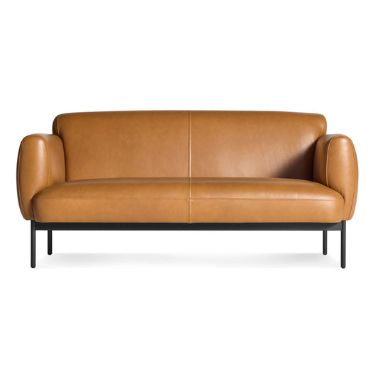 The Puff Puff Studio Sofa in Canyon Leather features a modern design with rounded arms, a smooth backrest, and black metal legs, displayed against a white background.