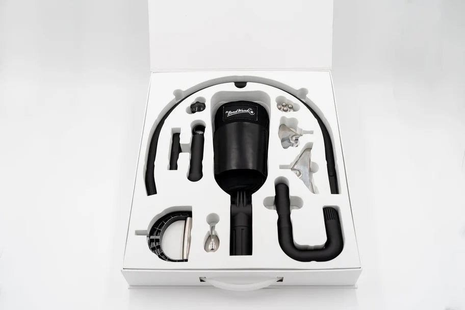 A neatly arranged case containing various components of a vacuum cleaner, including a flexible hose, different nozzles, brush attachments, and the main vacuum unit. The components are organized in a white foam insert for secure packaging.